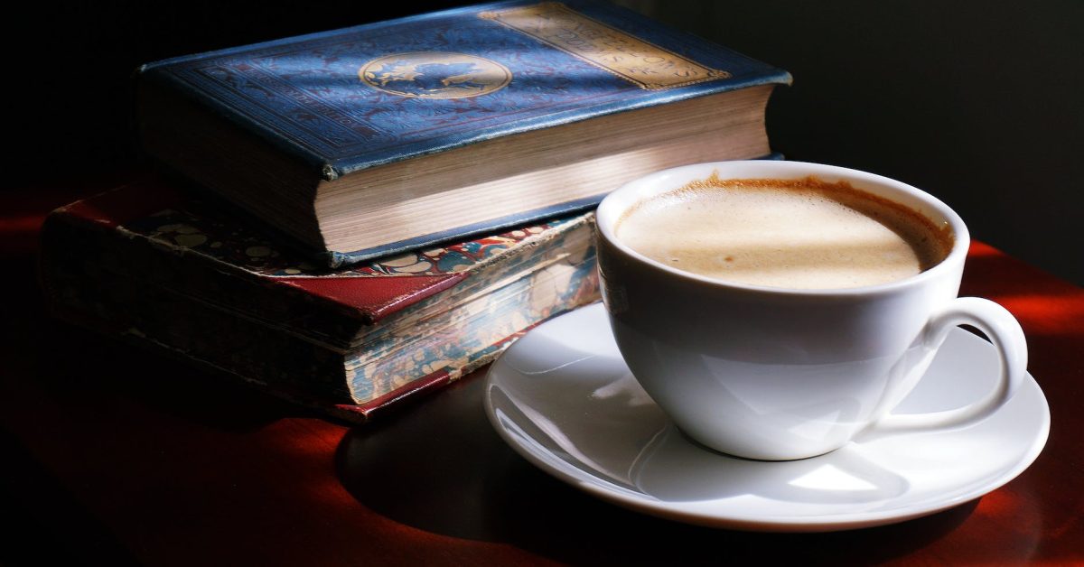 white teacup and saucer beside books
